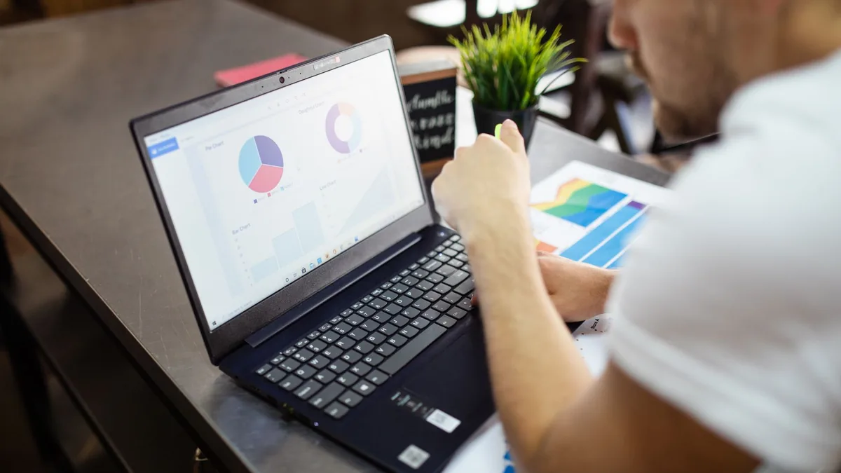 A laptop showing a rising analytics chart on a desk