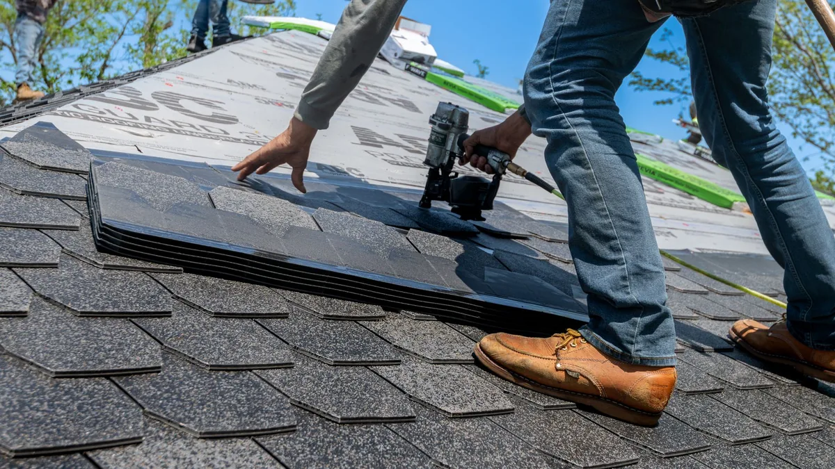 A roofer working on roof shingles